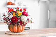 Pumpkin With Autumn Flowers On Counter In Kitchen