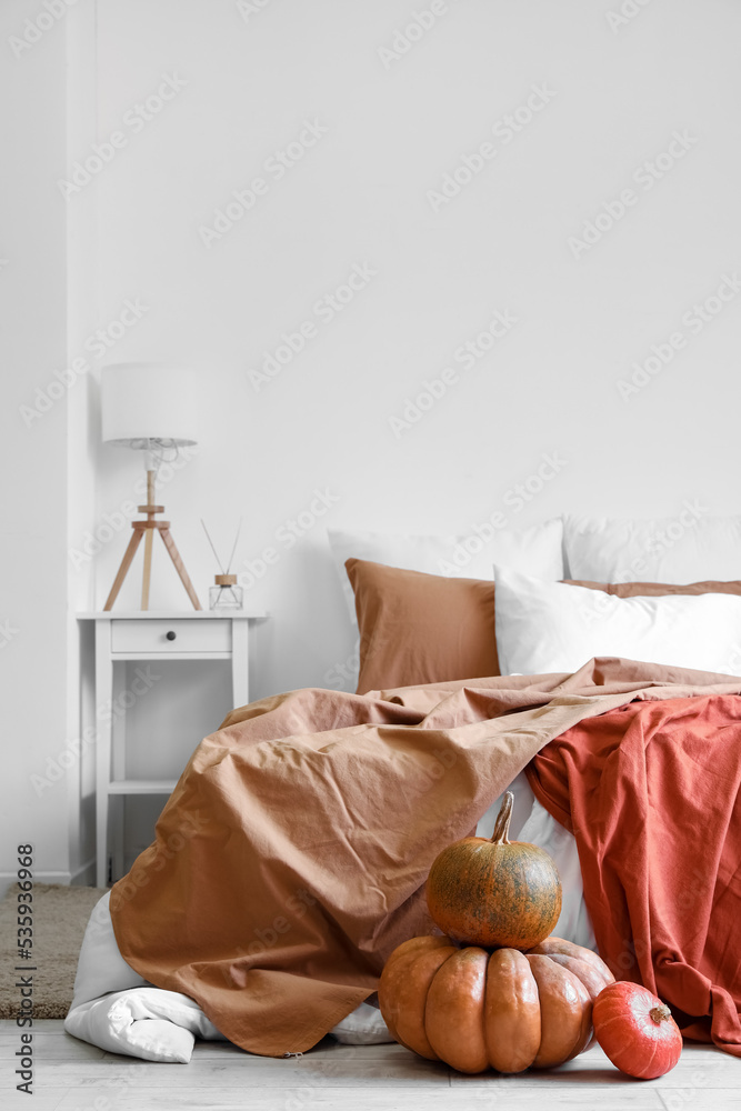 Interior of cozy bedroom with pumpkins and lamp