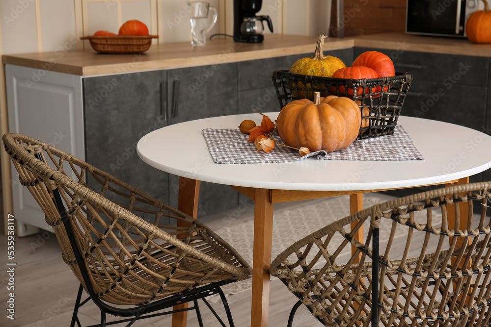 Basket with Halloween pumpkins on dining table in modern kitchen