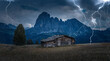 View of traditional wooden mountain chalets on scenic Alpe di Siusi with famous Langkofel mountain peaks in the background in storm weather, havy rain and lightnings, Dolomites, South Tyrol, Italy
