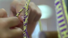 Hand Weaving Of Braids Using Yellow And Purple Yarn, Filmed As Extreme Close Up