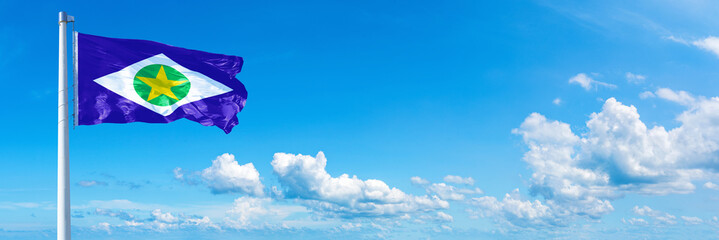 Wall Mural - Mato Grosso - state of Brazil, flag waving on a blue sky in beautiful clouds - Horizontal banner