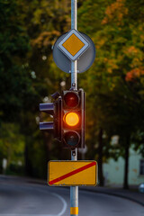 traffic semaphore with yellow light on defocused background of autumn city, closeup