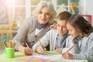 Wall Mural - Portrait of grandmother with kids drawing at home