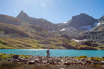 Wall Mural - The girl rises uphill against the background of a blue turquoise lake. Mountain landscape. A place for a healthy lifestyle. Caucasus, Russia