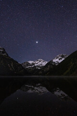 lake vilsalpsee in tannheimer valley in the night with stars and with snow on the mountain peaks