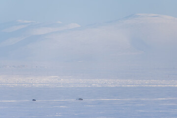 Wall Mural - cars are driving on snow and ice. winter arctic landscape with tundra and mountains. winter ice road