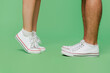 © ViDi Studio - Cropped close up side view photo shot caucasian young couple two friends family man woman wears basic sneakers shoes together standing on toes isolated on pastel plain light green background studiov.