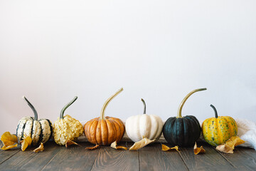 Multicolored pumpkins and dry autumn leaves on wooden background. Top view for Autumn, fall, Thanksgiving concept. .Autumn background