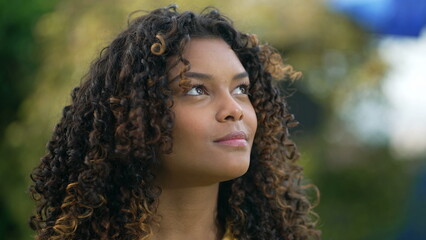 One black young woman looking up at sky smiling with HOPE and FAITH. Spiritual 20s adult African American girl closeup face feeling grateful