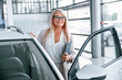 © standret - Manager is ready to help. Woman in white formal clothes is in the car dealership