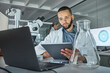 © N Felix/peopleimages.com - Tablet, laptop and laboratory man with glass beaker in medical research, healthcare innovation study or vaccine data analysis. Thinking scientist, medicine worker or technology for future dna science