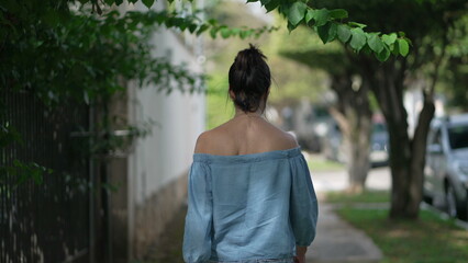 Back of mature woman walking in green city street. One middle aged 50s female person walks in sidewalk in contemplation 2