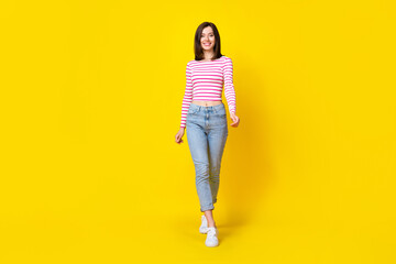 Sticker - Full size photo of cute pretty cheerful woman brunette hairdo wear striped shirt jeans walking going isolated on yellow color background