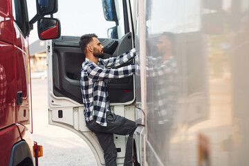 Opening the door. Young truck driver is with his vehicle at daytime