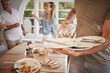 © David Lahoud/peopleimages.com - Lunch, family and man cleaning dishes from table after eating meal. Clean up, packing away and clearing plates from dinner table after family lunch together. Household, helping and dinner at home