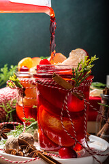 Wall Mural - Hot mulled wine with cinnamon and star anise. Winter autumn fruit and berry grog, hot punch drink with orange, apple, cranberry, spices, with Christmas tree branches and gift boxes on wooden table 