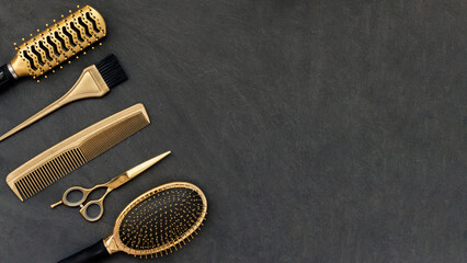 Hairdressing tools in gold on gray concrete background. Hair salon accessories, combs, scissors in the corner and copy space