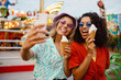 © Drobot Dean - Young multiracial women taking selfie on cellphone in attraction park