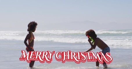 Sticker - Animation of merry christmas over happy african american children playing on beach