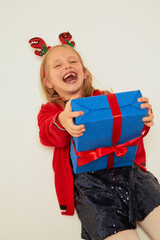 Wall Mural - Smiling funny child (kid, girl)  holding Christmas gift box