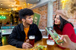 © ADDICTIVE STOCK - Content ethnic couple sitting at table with beer in bar