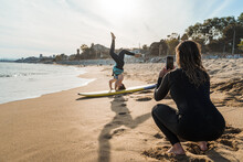 Women Surfers Doing Exercises And Taking Photo On Beach