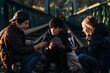 © ADDICTIVE STOCK - Group of three children playing cards in a train track