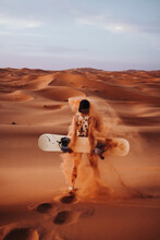 Young Woman Standing On Sand Ready For Sandboarding