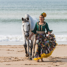Woman In Gypsy Flamenco Dress Strolling With Horse On Ocean Coast