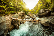Woman Sitting On Wooden Trunk Above Mountain River