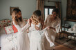 © ADDICTIVE STOCK - Cheerful women helping lady to clothe dress in bedroom
