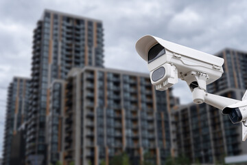 Poster - Panoramic view of CCTV surveillance camera with blurred apartment building background with copy space for background banner.