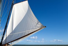 Ship Mast And A White Sail On A Blue Sky