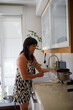 © ADDICTIVE STOCK - Cheerful middle aged woman in kitchen at sink