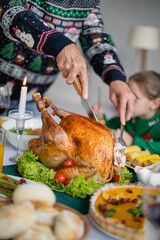 Wall Mural - partial view of senior man cutting traditional thanksgiving turkey near blurred granddaughter