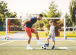 man with child playing football outside on field