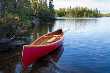 Wall Mural - red wood canoe on the shore of a boundary waters lake in morning light during autumn