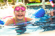 Smiling cute little caucasian girl in outdoor pool in sunny day.