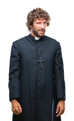 Canvas Print - Handsome hispanic catholic priest man over isolated background winking looking at the camera with sexy expression, cheerful and happy face.