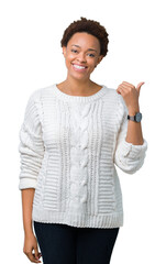 Sticker - Beautiful young african american woman wearing sweater over isolated background smiling with happy face looking and pointing to the side with thumb up.