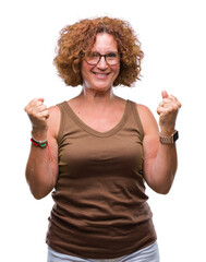 Poster - Middle age hispanic woman wearing glasses over isolated background celebrating surprised and amazed for success with arms raised and open eyes. Winner concept.