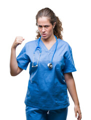 Sticker - Young brunette doctor girl wearing nurse or surgeon uniform over isolated background angry and mad raising fist frustrated and furious while shouting with anger. Rage and aggressive concept.