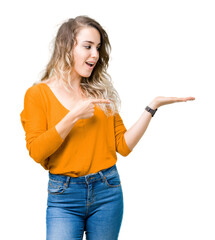 Beautiful young blonde woman over isolated background amazed and smiling to the camera while presenting with hand and pointing with finger.