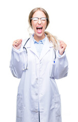 Sticker - Beautiful young blonde doctor woman wearing medical uniform over isolated background excited for success with arms raised celebrating victory smiling. Winner concept.