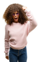 Wall Mural - African american woman wearing a pink sweater annoyed and frustrated shouting with anger, crazy and yelling with raised hand, anger concept