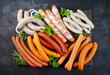 Traditional raw grill platter with different types of bratwursts prepared for a summer barbecue offered as a top view on a rustic board