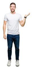 Sticker - Handsome man wearing casual white t-shirt smiling cheerful presenting and pointing with palm of hand looking at the camera.