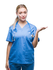 Sticker - Young blonde surgeon doctor woman over isolated background smiling cheerful presenting and pointing with palm of hand looking at the camera.