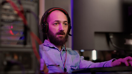 Wall Mural - Handheld shot of gamer with headset streaming gameplay shouting after winning online multiplayer game on gaming pc setup. Caucasian man celebrating victory in online computer competition with friends.